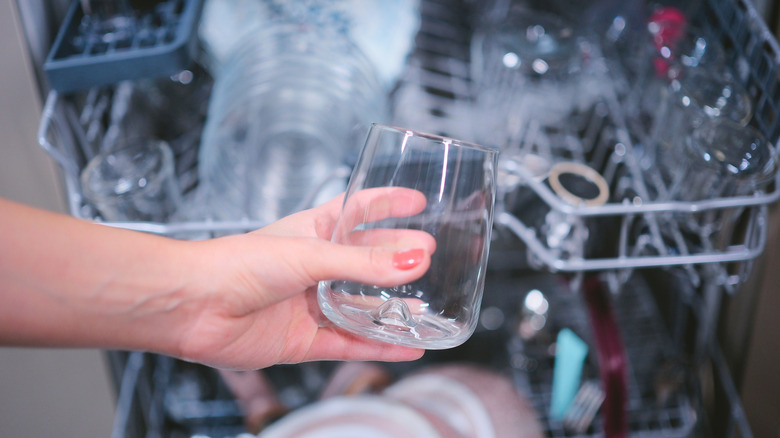 Woman putting glass in dishwasher