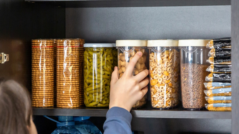 A woman pulling out goods from her pantry