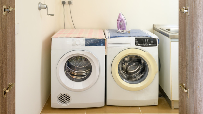 An iron sitting on a dryer in a laundry room