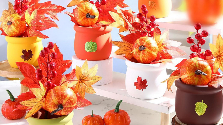 A pack of centerpieces featuring jars with glittery designs, pumpkins, and foliage