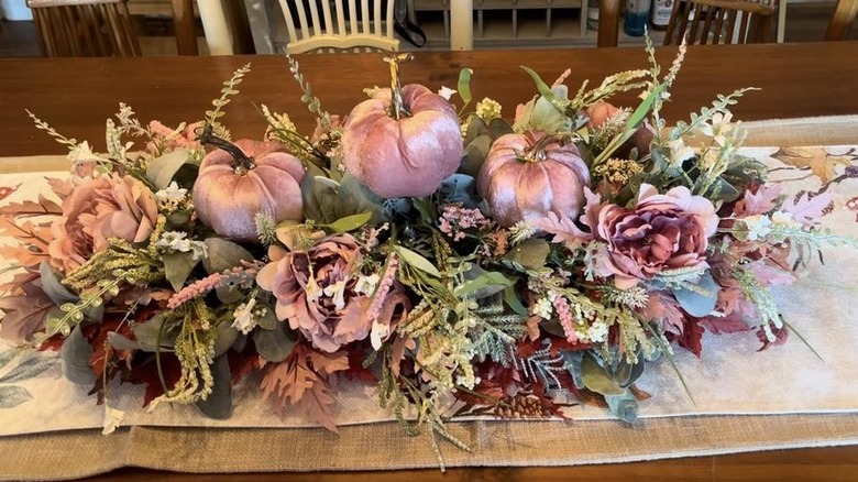 A floral arrangement in the center of a dining table with three velvet pumpkins from Dollar Tree