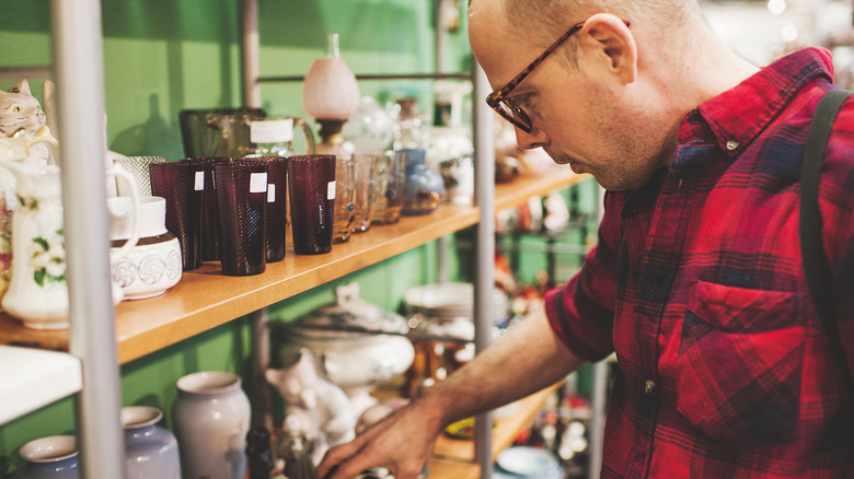 A man in a red flannel shopping for home goods in a thrift store