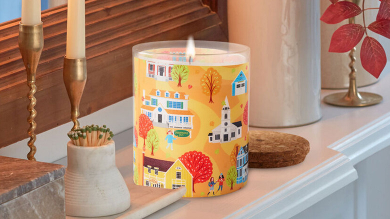 A Gilmore Girls candle on a mantle surrounded by fall colors and other decor