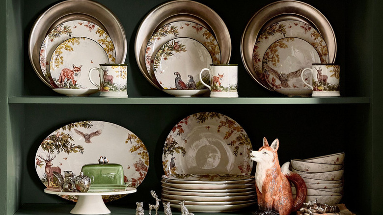 A cabinet filled with plates, cups, and decor from pottery barn