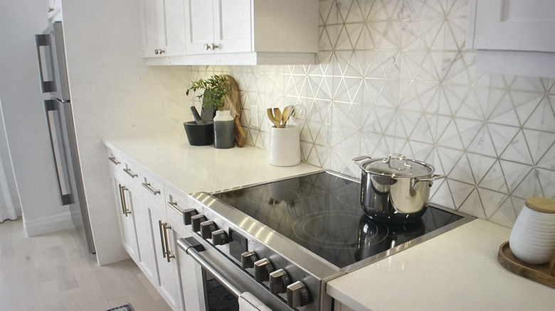 White kitchen counters and cabinetry with triangle tile inlaid with brass