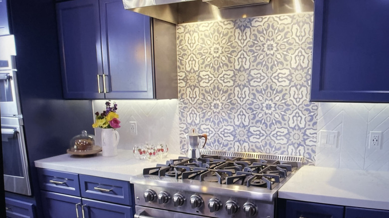 Kitchen with deep blue cabinetry, gas range, and Moroccan quatrefoil rosette tile backsplash