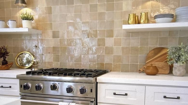 Glazed terracotta square tile kitchen backsplash with floating shelves and small gas range