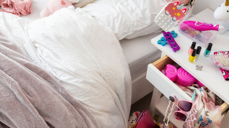 Close up of a messy nightstand next to an unmade bed