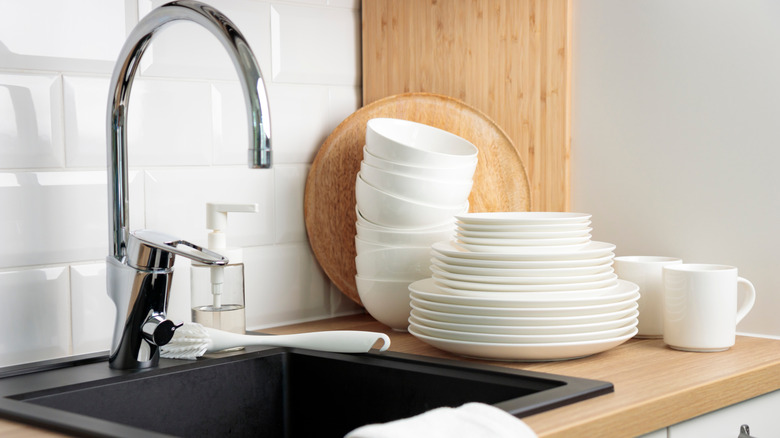 A sink with clean dishes piled up beside it