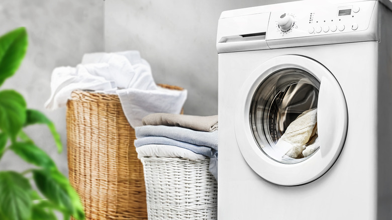 A washing machine next to two tidy laundry hampers