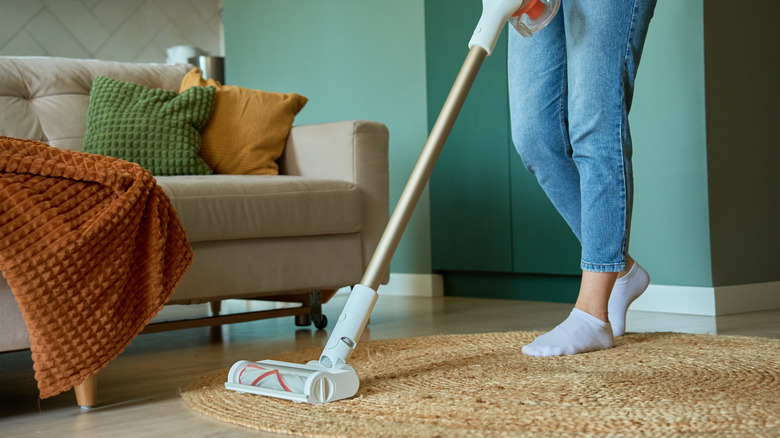 A person vacuuming the floor of a modern apartment living room