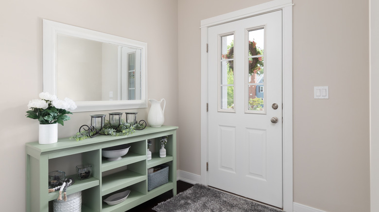 A cozy entryway with a teal table and a white wall mirror