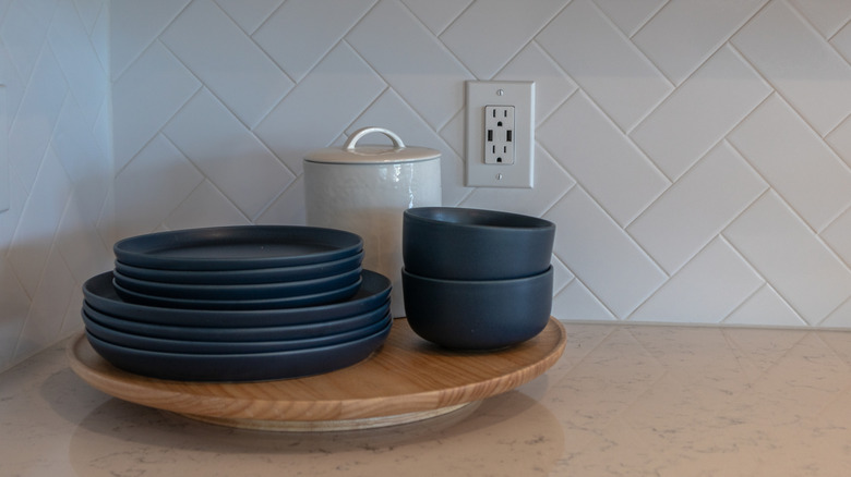 A lazy Susan in a kitchen holding plates and bowls