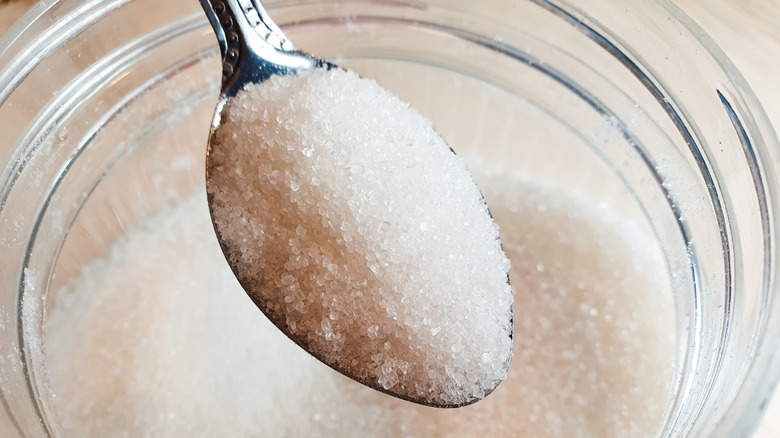 Close-up of a spoonful of sugar over a sugar dish