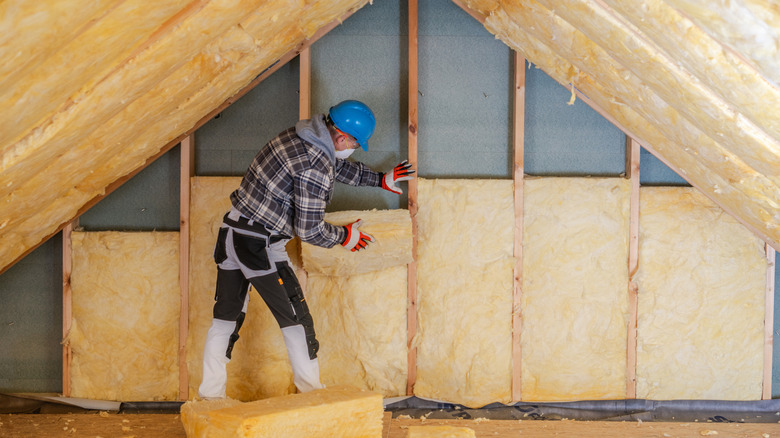 A worker installing insulation in a loft