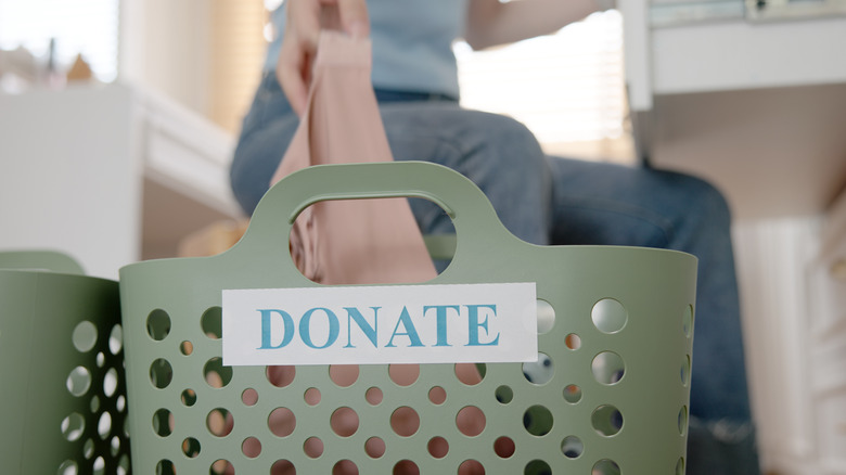 Person putting item into plastic hamber labeled 'donate'