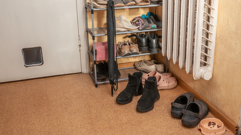 An entryway with shoe storage and an umbrella beside a radiator with scattered shoes on the floor