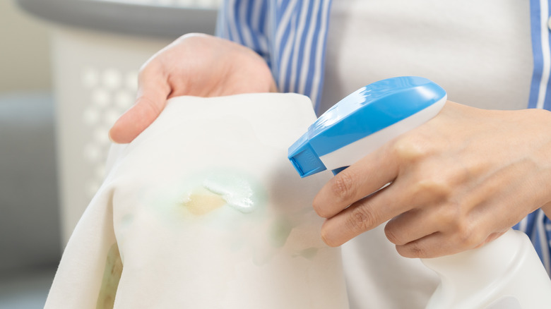 Person spraying pre-treating chemical on stained cloth