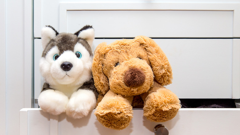 two stuffed animals peeking out of cabinet