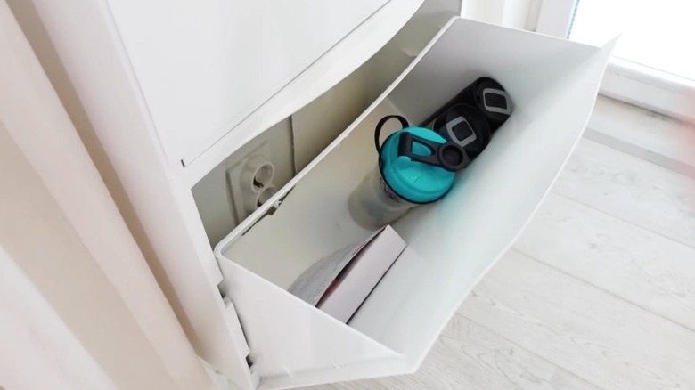 water bottles and towles in a tilt out shoe cabinet