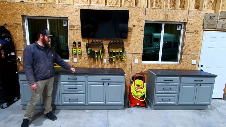 Person shows off his garage workbench area made using old kitchen cabinets painted light blue