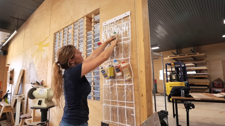 Person filling an over-the-door shoe rack with bottles