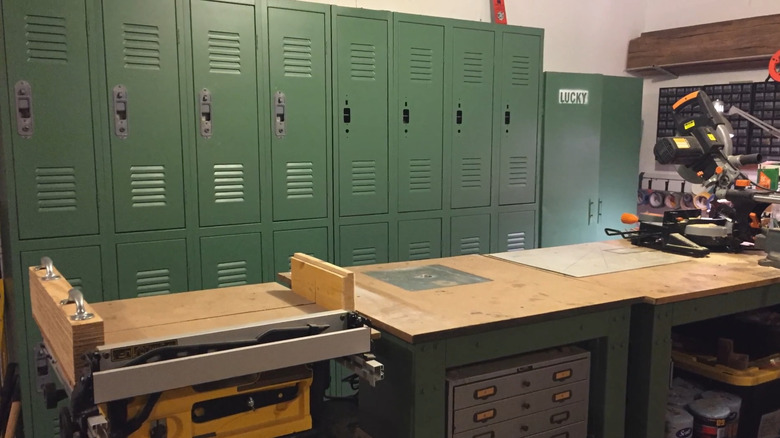 Rows of green school lockers in a garage next to a large workbench