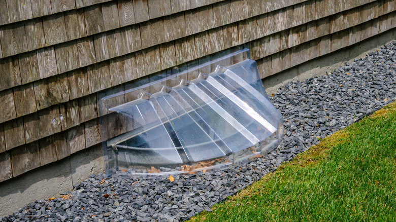 A plastic cover over a window well in a yard