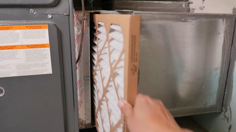 Hand sliding in a new filter into an HVAC unit