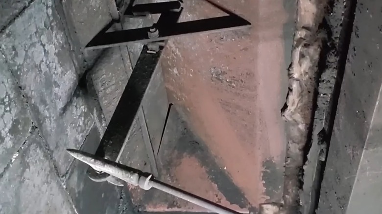 Using a poker to close the damper on a fireplace