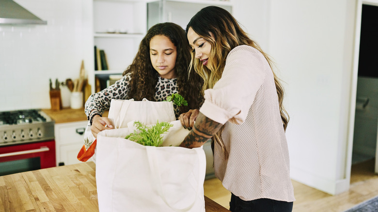Mother and daughter unloading groceries