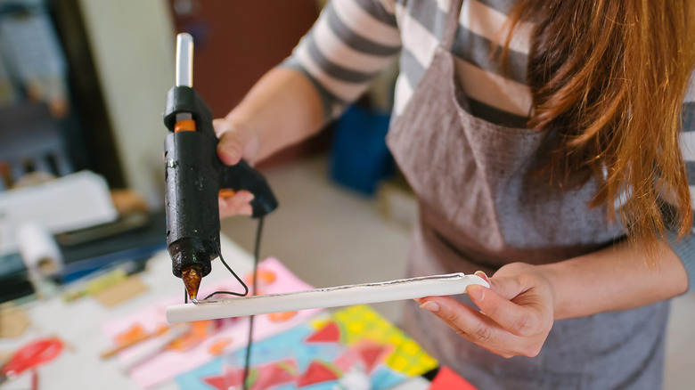 Young woman gluing with hot glue gun
