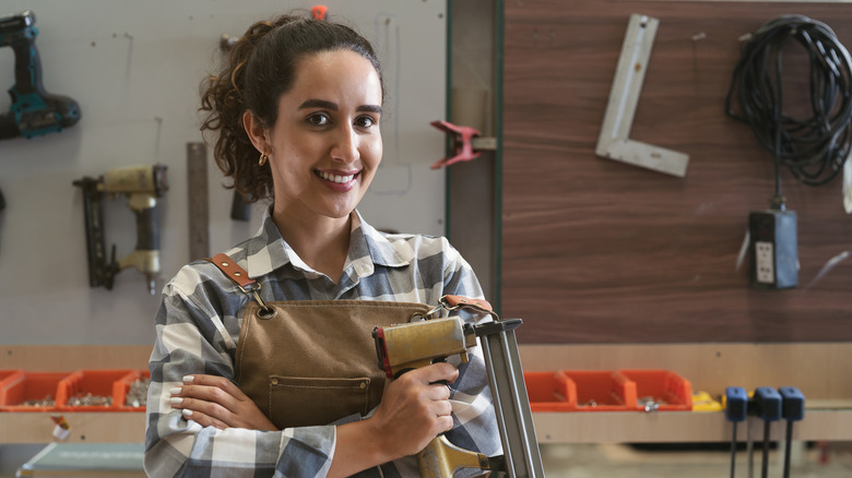 woman in workshop hollding nail gun