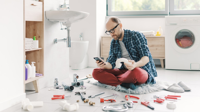 confused man sits on floor trying to find the right tool