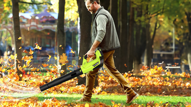 A man uses a Wolfmen Electric Cordless Leaf Blower to clear a path