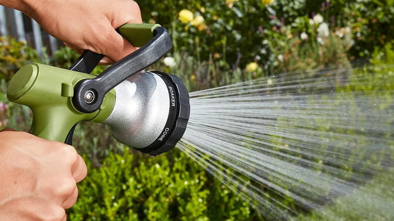 A person adjusts the handle of a Greenwood No-Squeeze Fireman's Nozzle to water their grass