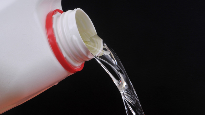 Bleach being poured out of a white container with red seal