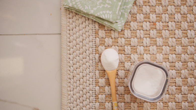 A spoon with baking powder on a brown and white carpet