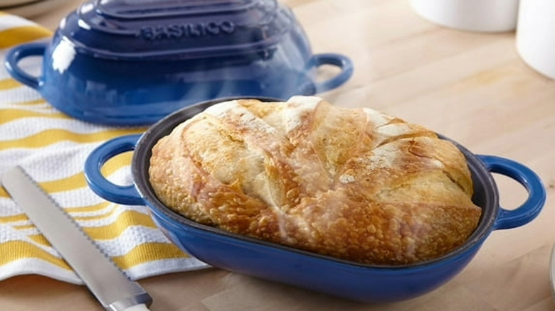 A oval Dutch oven for bread with fresh bread on table