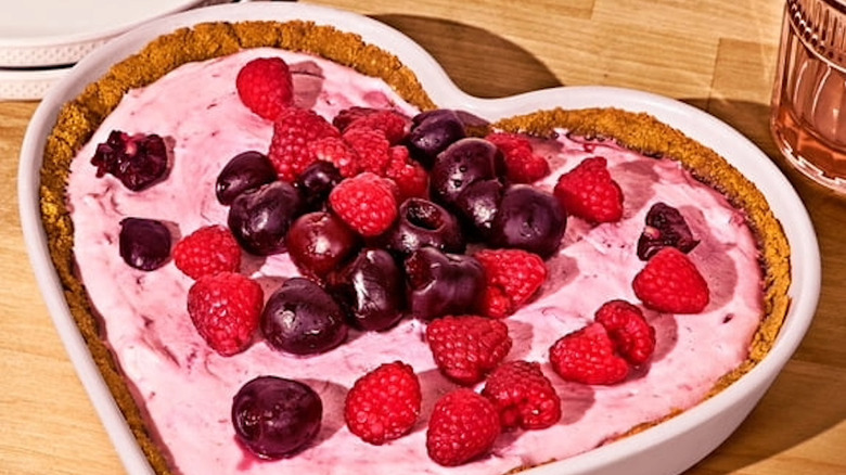 A pink heart-shaped dish with a tart baked in it