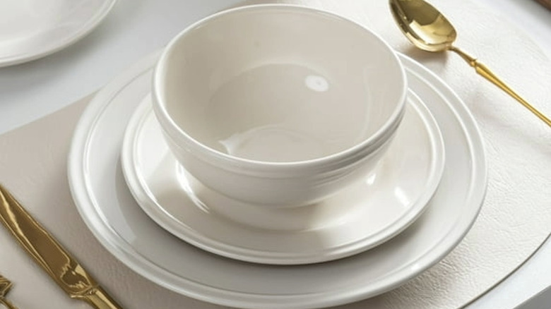 A white bowl with other white dishes arranged on a table