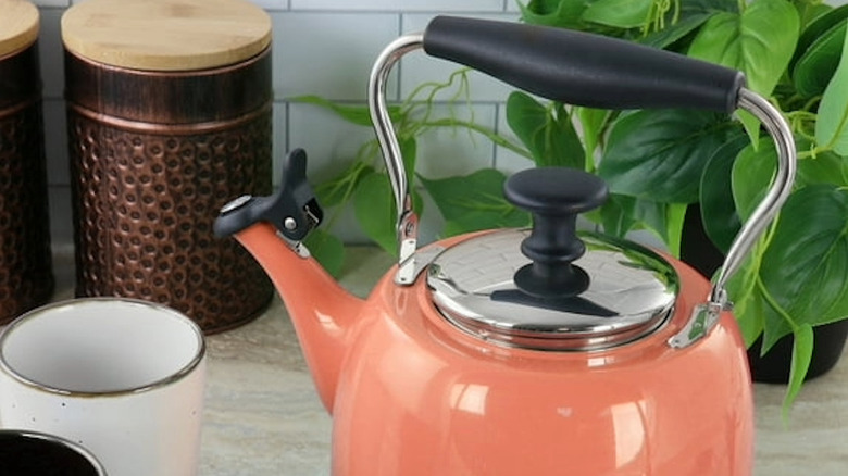 A coral colored tea kettle sitting on a counter
