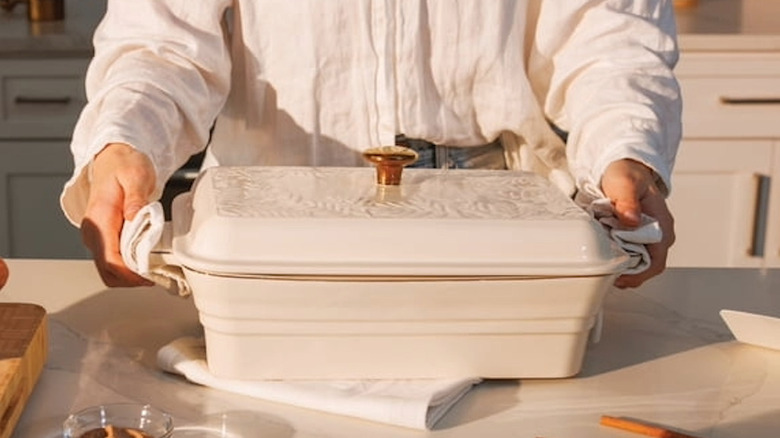A person holding a long rectangular casserole dish