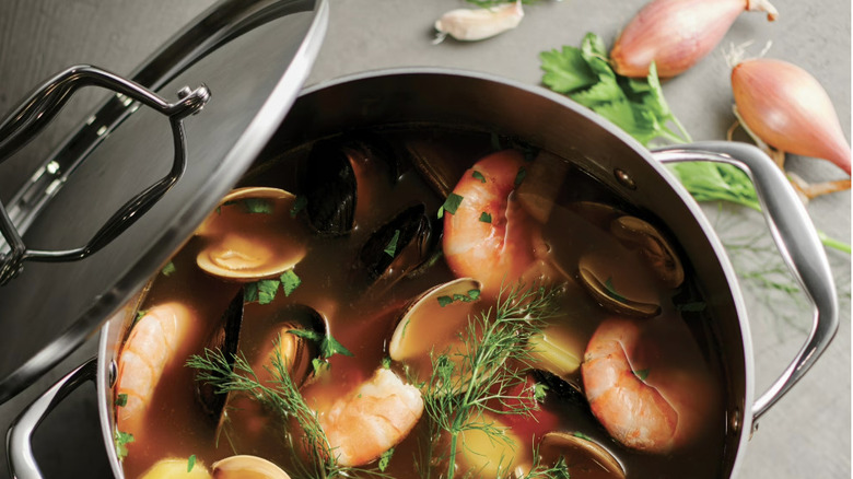 A large stockpot with stainless steel finish holding a seafood soup