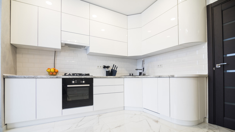 A kitchen with lacquered white cabinets and a black stove