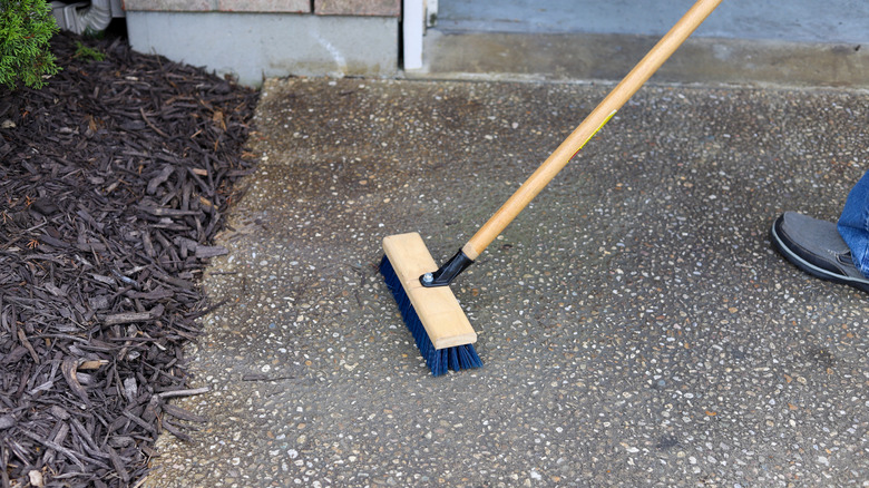 Push broom sweeping mulch off an asphalt driveway