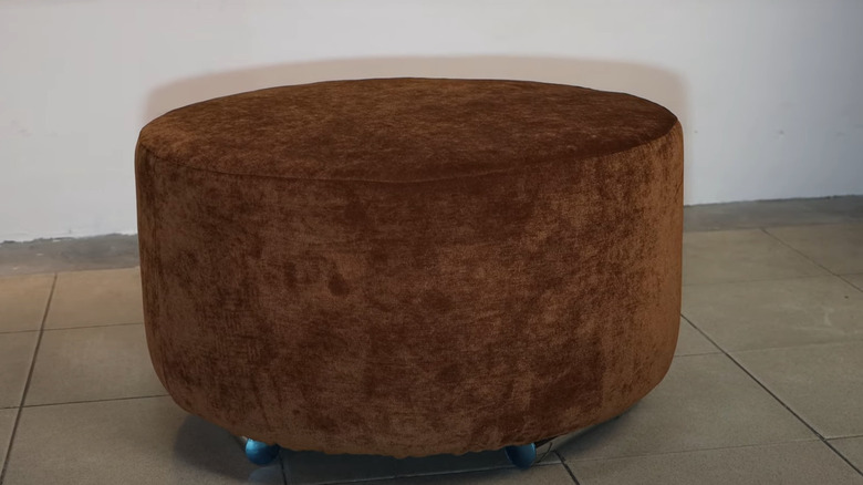 Brown velvet ottoman tire on tile floor