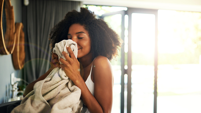 A woman happily smelling laundry