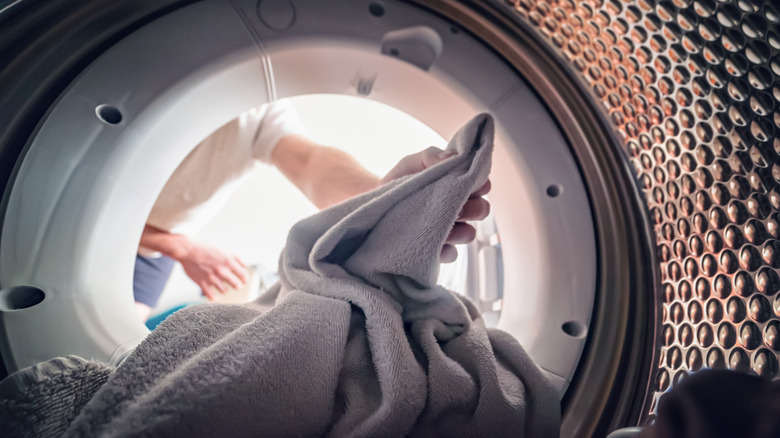 Someone loading laundry into a front loading washing machine
