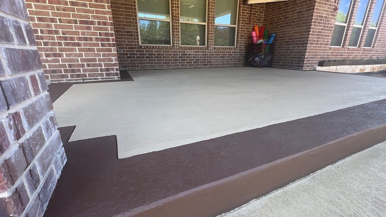 A brown painted border on a concrete slab patio.